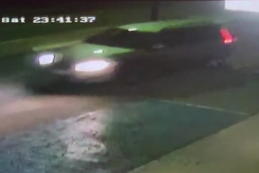 A blurry CCTV photo of a car at night time.