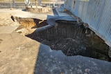 A sinkhole on a cement walkway.