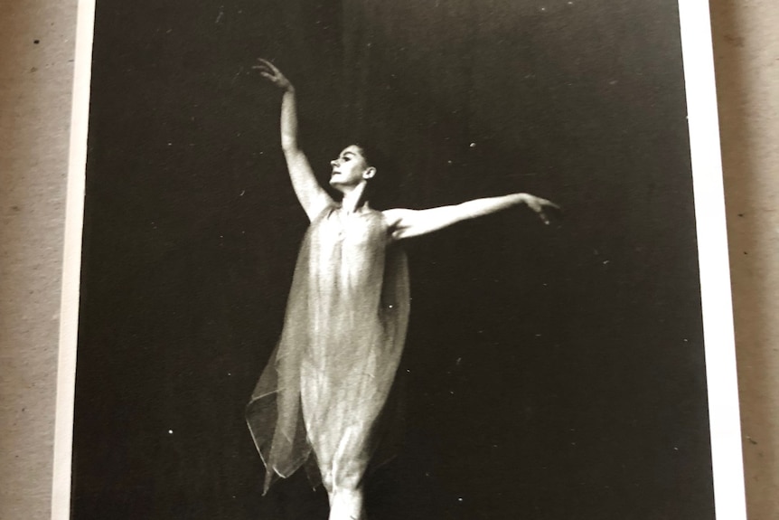 Black and white portrait of a woman dancing ballet, wearing a flowing dress, standing on her toes and arms.