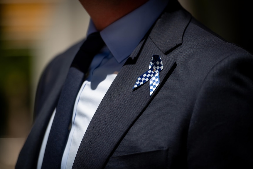 A lapel pin with police colours worn by a mourner.