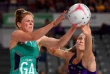 A Melbourne Vixens Super Netball player competes for the ball alongside a Queensland Firebirds opponent.
