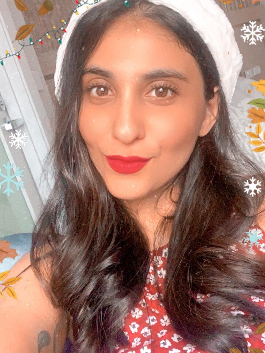 Deepa Rao wearing a Christmas hat, red lipstick and a red top in a photo decorated with snowflakes.