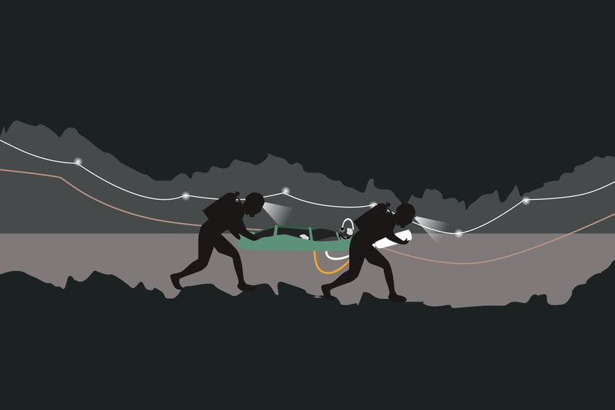 An illustration shows two divers guiding a stretcher through an underground passage.