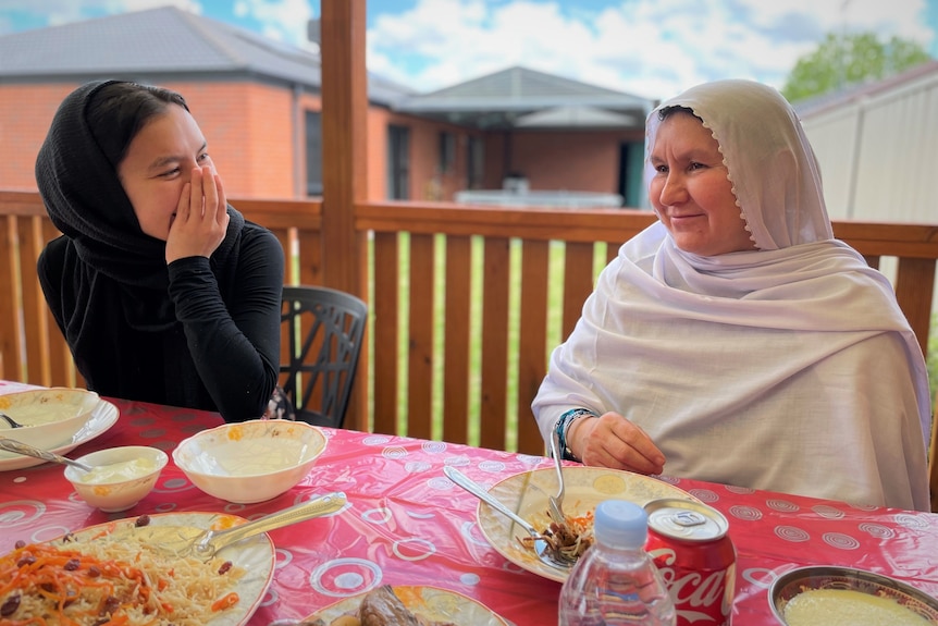 A girl and woman sit at a table smiling