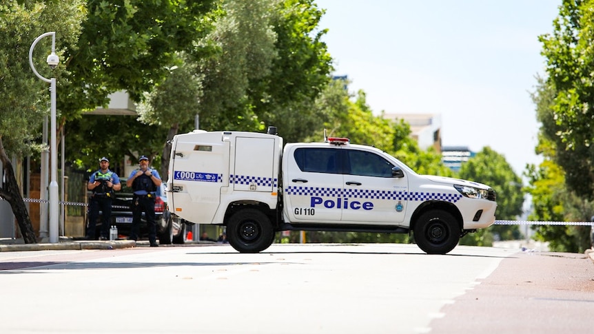 Police standing behind crime tape