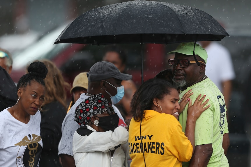 A crowd of people, some crying, outside a US supermarket after a shooting