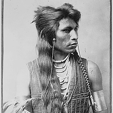 A black and white image of a Native American man with long hair.
