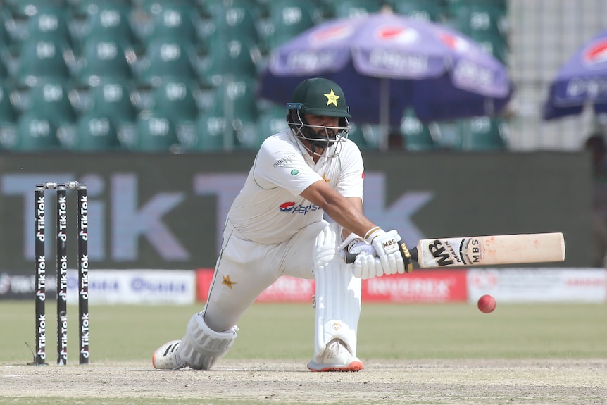 Azhar Ali kneels and holds a cricket bat out in front of him at full stretch