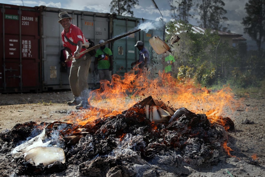 A man sets fire to a pile of ballot papers.