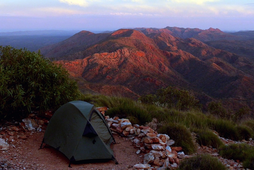 Tent in foreground with dark red hills in background
