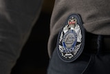 A navy blue police badge on the jumper arm of a police officer