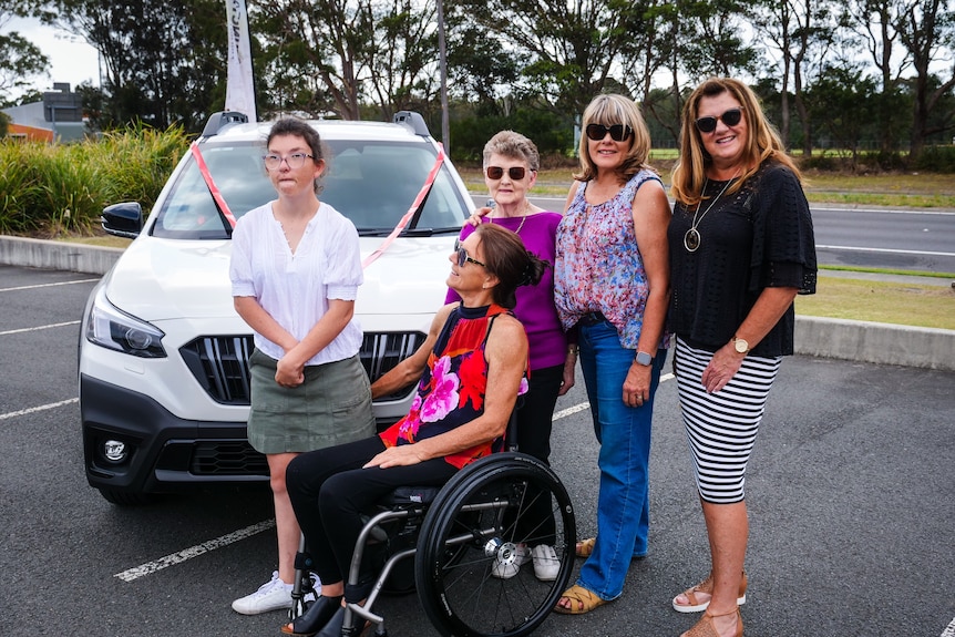 A group of women standing by a car.