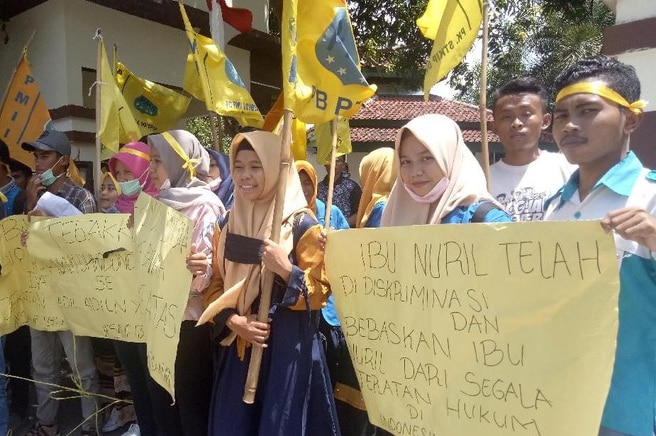 Sekelompok orang berbaris membawa sejumlah bendera dan spanduk