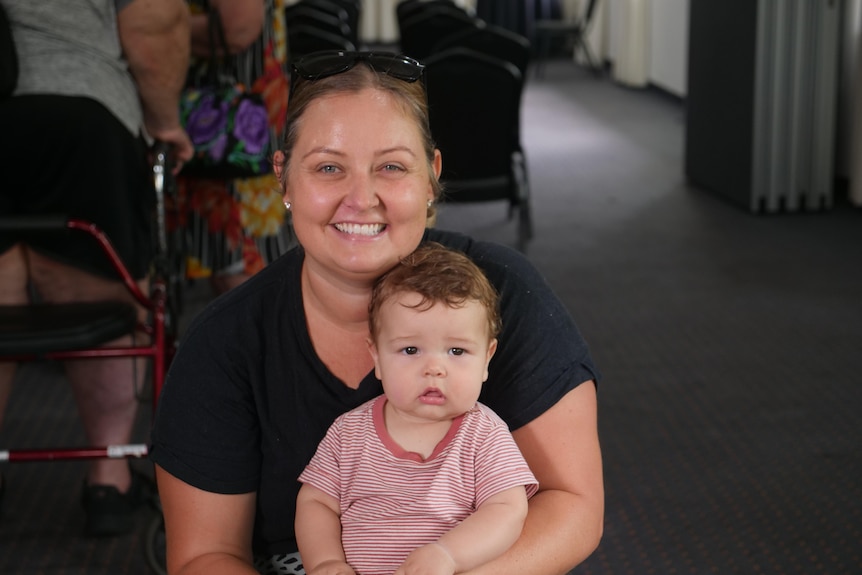 A woman is sitting down holding a baby boy in her arms