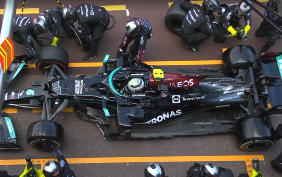 Pit crew try to remove tyres from a race car.