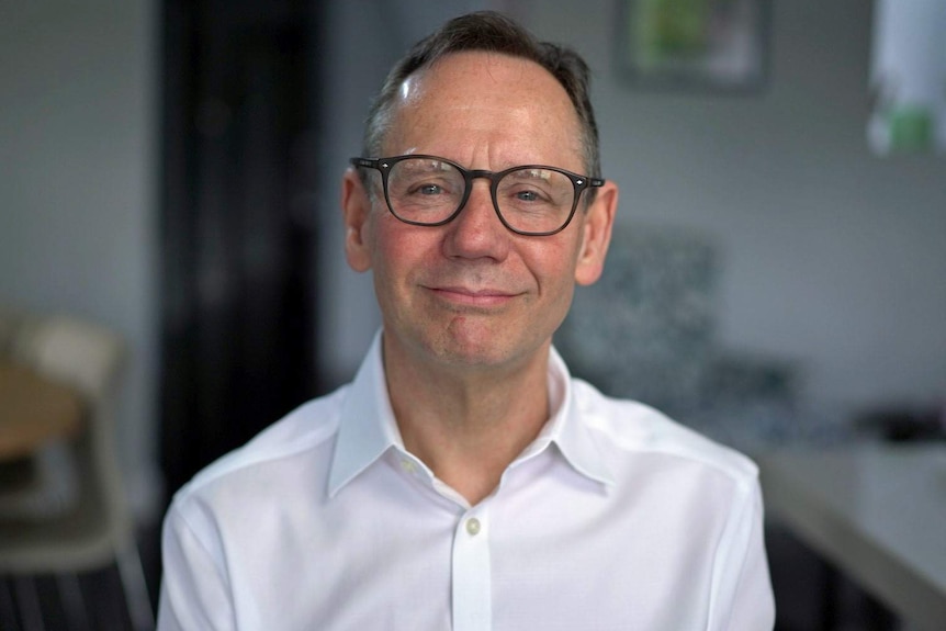 A man wearing glasses and a white collared shirt.