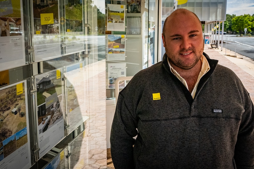 Real Estate Agent, Rhys Peacock stands in front of the Ray White Barcaldine real estate window in May 2023.