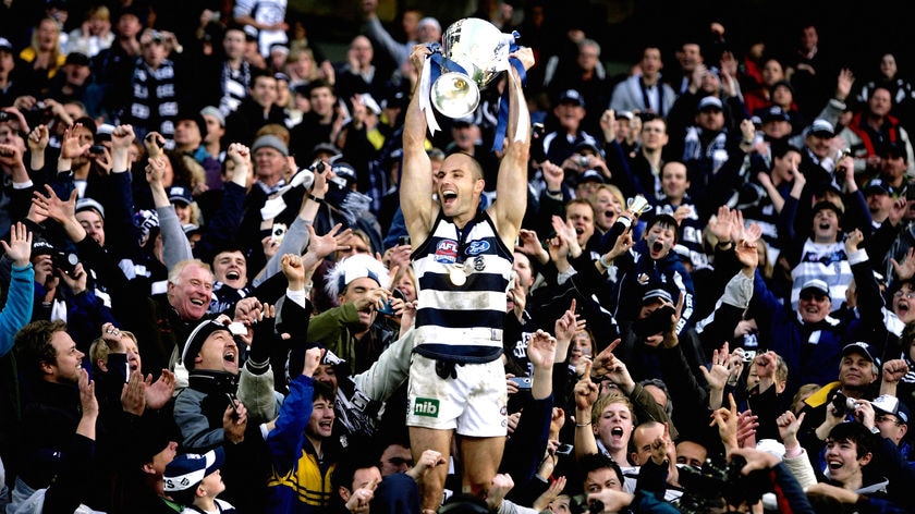 To the victors, the spoils: Cats skipper Tom Harley shows off the premiership cup to the fans.