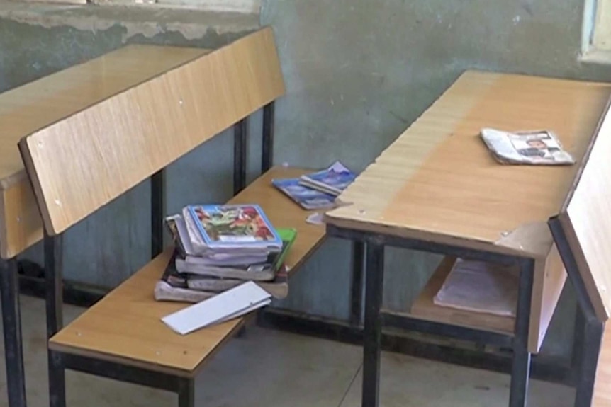 books on a wooden seat and table inside a schoolroom
