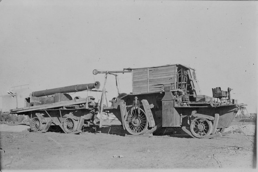 Black and white photo of giant tractor with man sitting on wheel