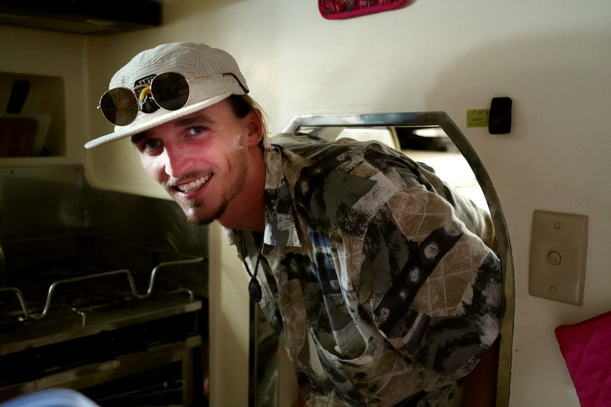 Young man heading out of a small door of a room quarters in a boat. 