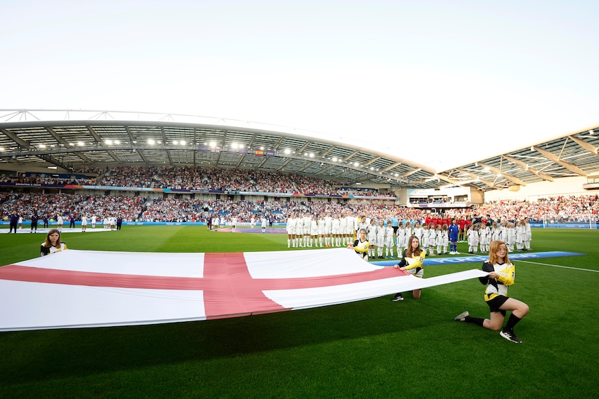 Deux équipes de football s'alignent avant un match avec un drapeau anglais au premier plan