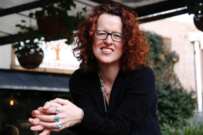 Genevieve Bell sits on a bench in cafe smiling.