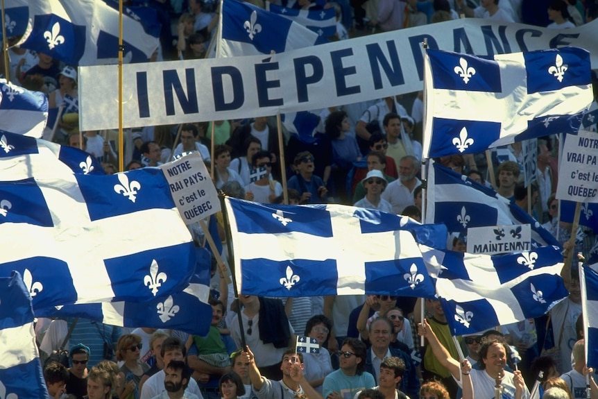 A sea of protesters march. One prominent banner in French reads 'independence'