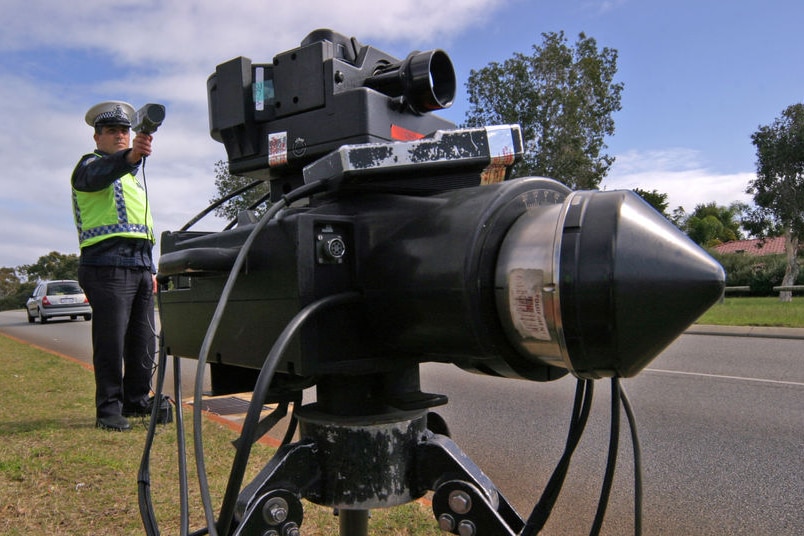 A policeman holding a speed radar behind a multanova camera