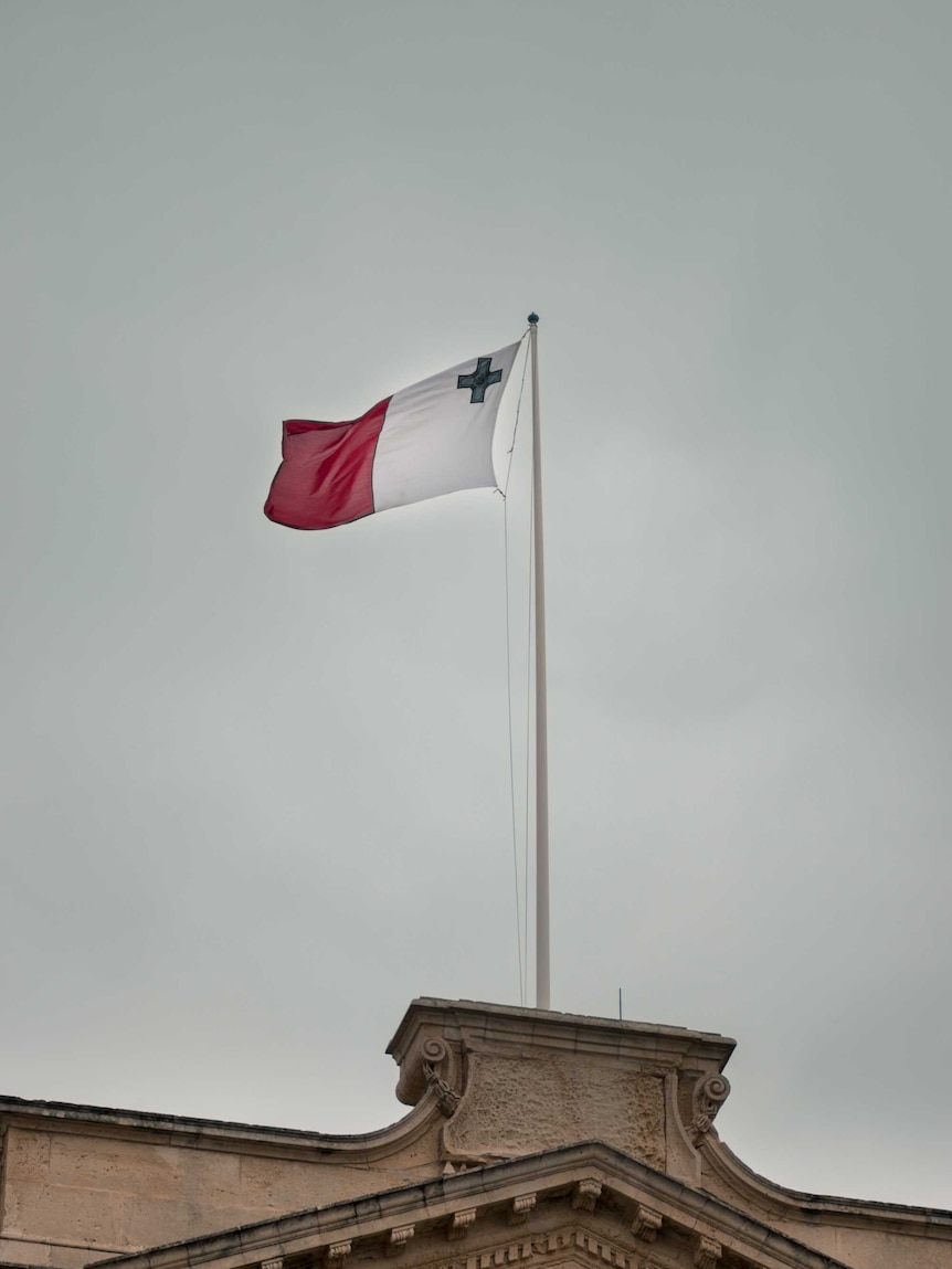 The red and white flag of Malta flies above a building.