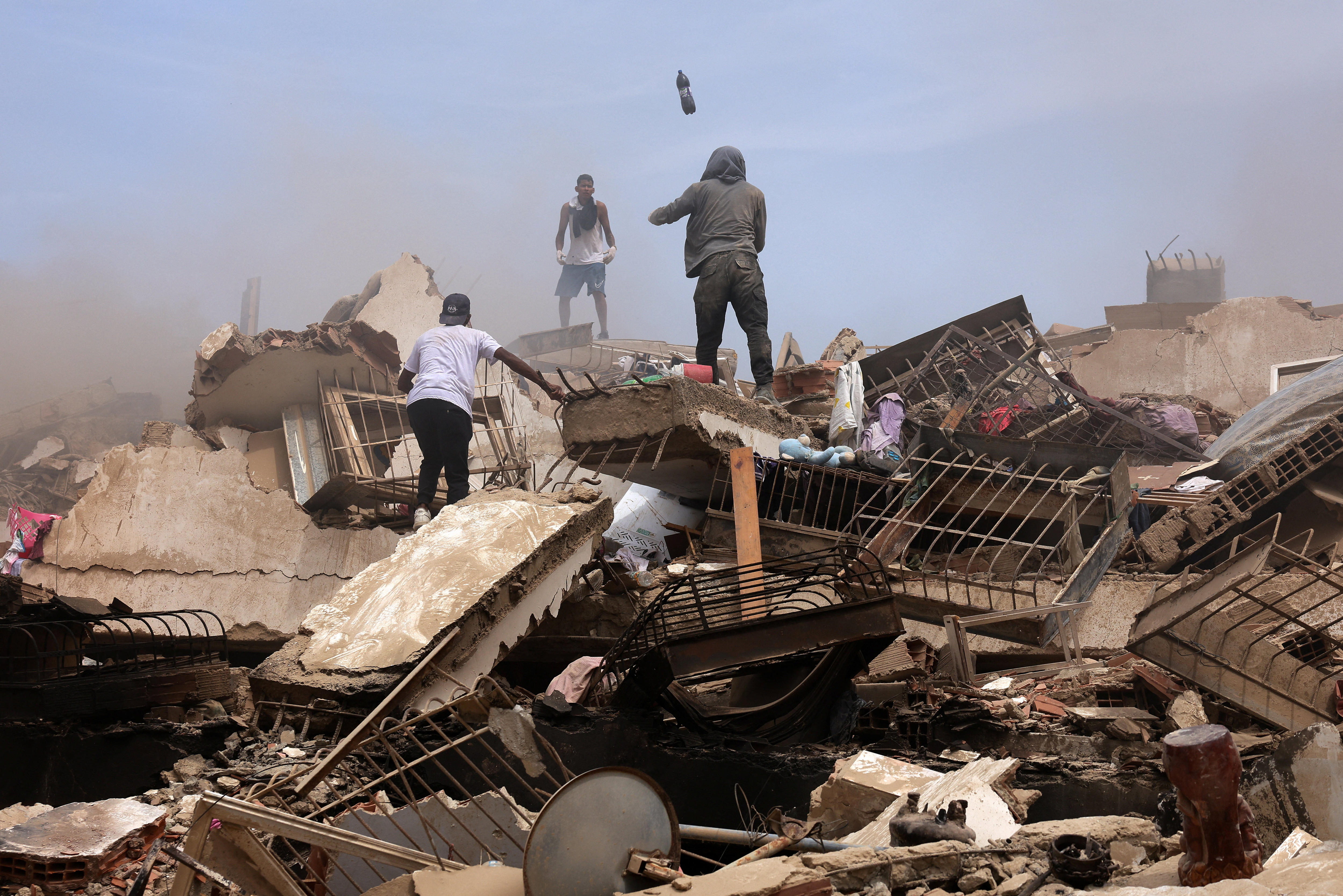 people stand on top of a collapsed building 