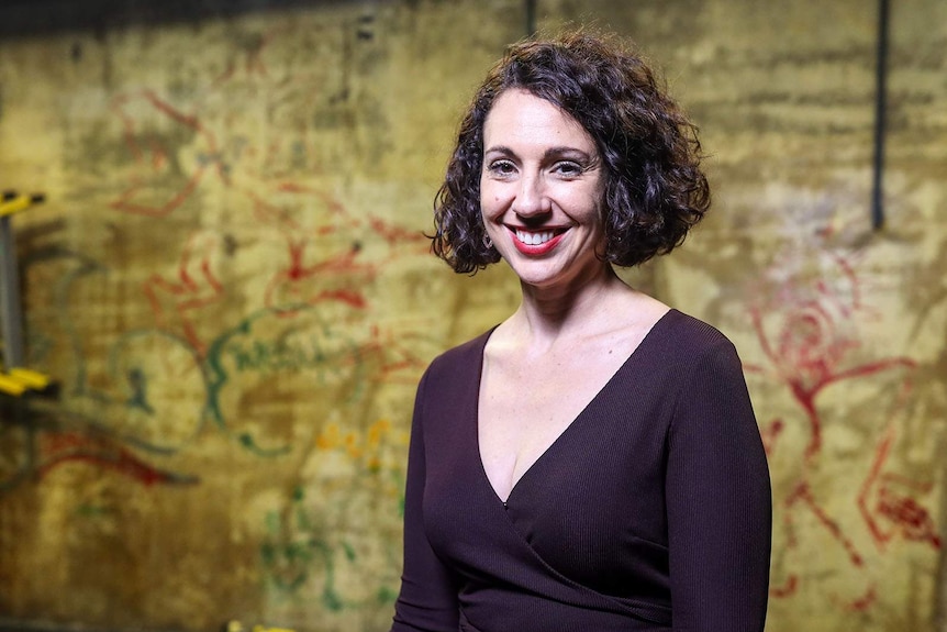 A smiling woman inside a large performance space