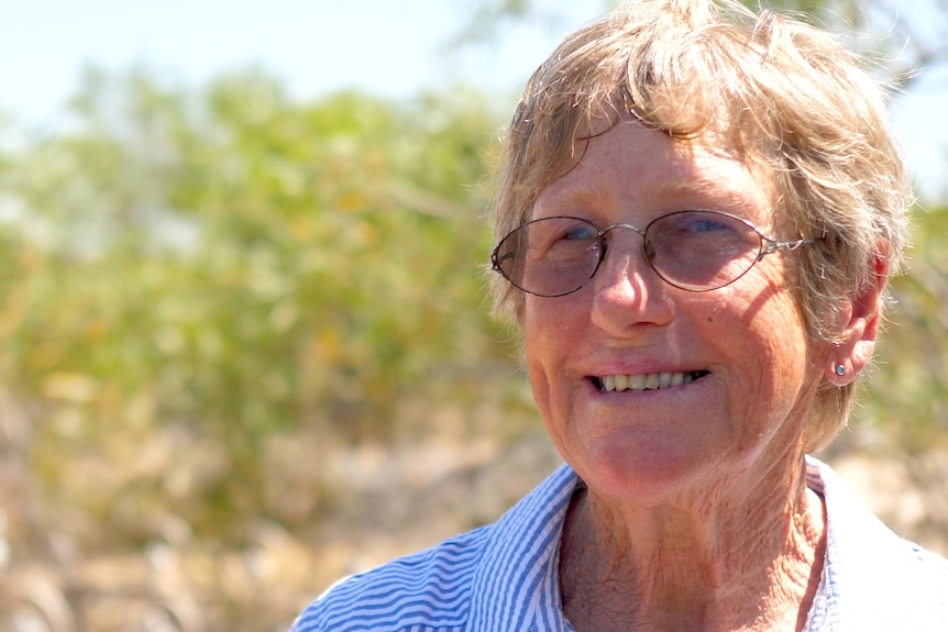 An older woman with glasses in the bush.