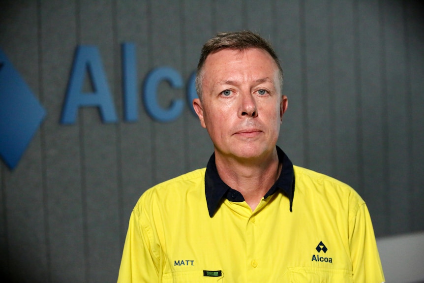 Headshot of a man in a yellow work shirt with Alcoa written on it