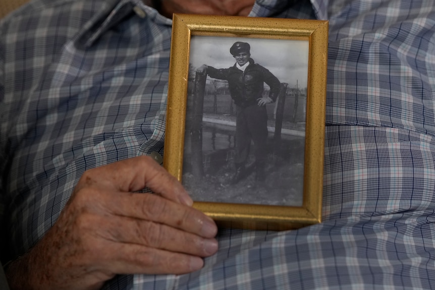 Harold holds a photo of himself at 20-years-old during the war. 