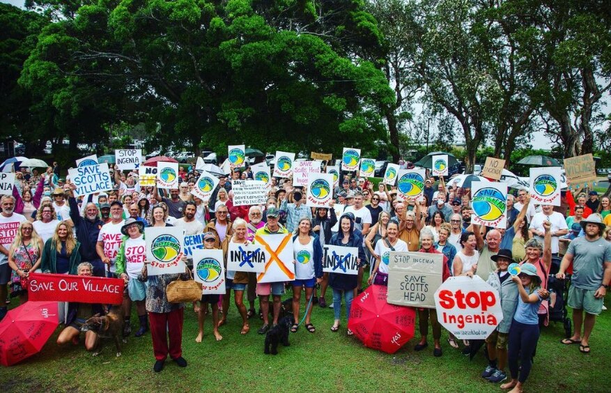 A large crowd of people gathered holding signs that say 'stop Ingenia' and 'save Scott's Head'