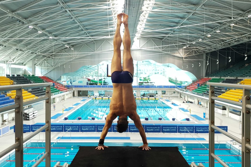 Diver Declan Stacey in a handstand position on a diving board.
