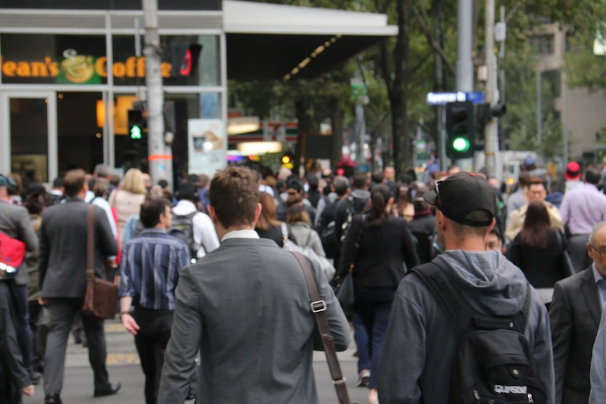 Crowds of pedestrians walk across a city street.