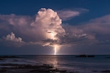 A lightning bolt shoots through clouds into water in Broome