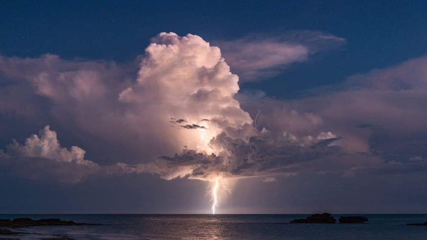 A lightning bolt shoots through clouds into water in Broome