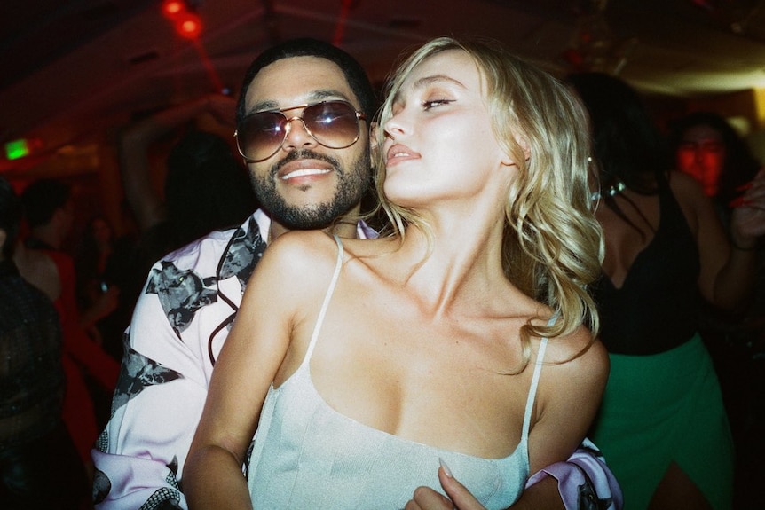 Abel Tesfaye and Lily Rose Depp in The Idol, with Tesfaye holding Depp from behind.