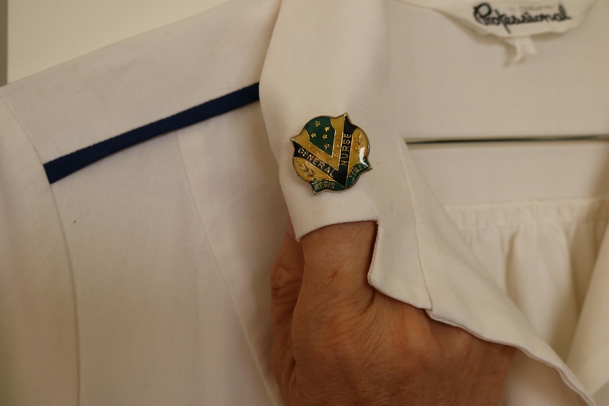 A nurses badge pinned on the collar of an old white uniform
