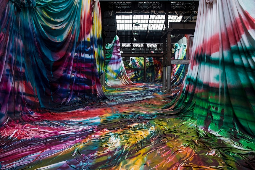 Interior of the industrial-style foyer of Carriageworks, featuring installation of brightly spray-painted and draped fabric.