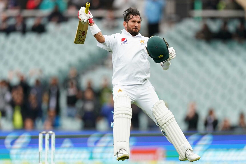 Yasir Shah jumps up and waves his bat while holding his helmet in delight.