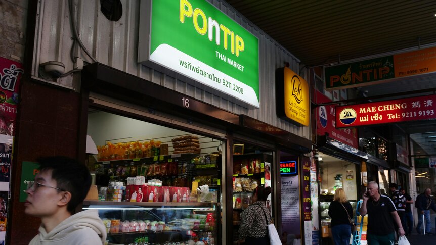 The front of a grocery store with English and Thai signage