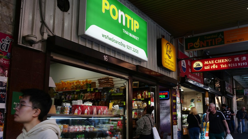 The front of a grocery store with English and Thai signage