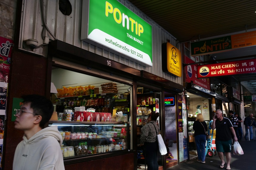The front of a grocery store with English and Thai signage
