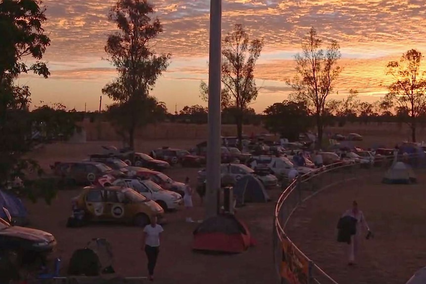 Cars near an oval at sunrise.