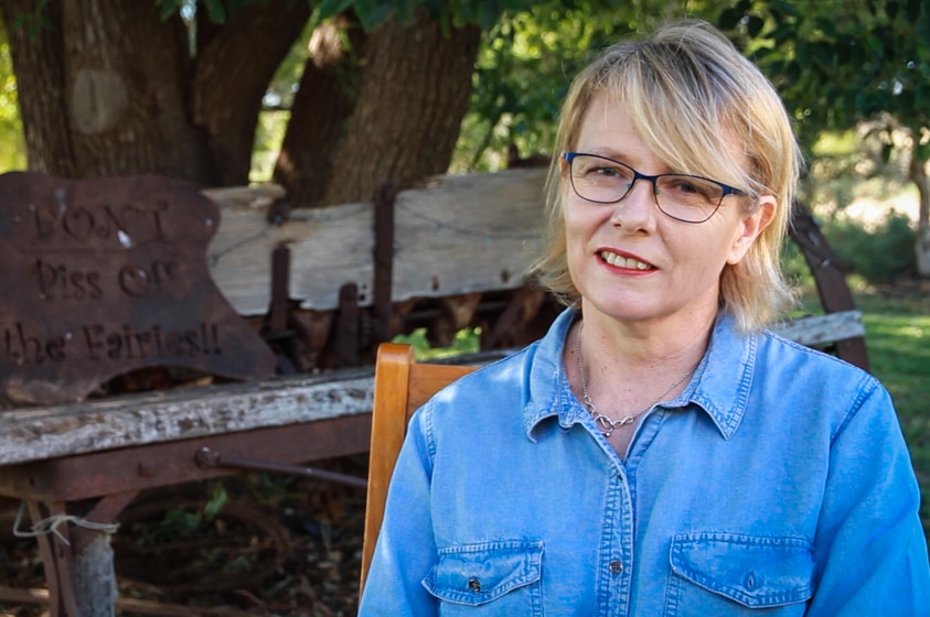 Woman with glasses in blue shirt sitting down