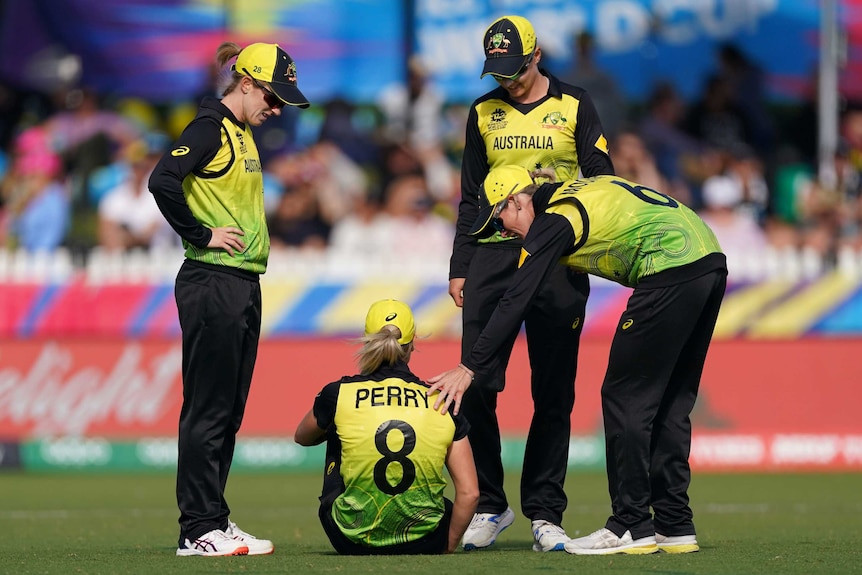 Australian teammates crowd around an injured player sitting on the ground during the Women's T20 match against New Zealand.